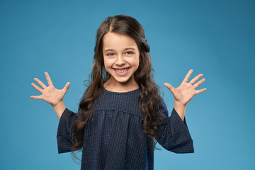 Positive girl in grey dress showing fingers, hands.