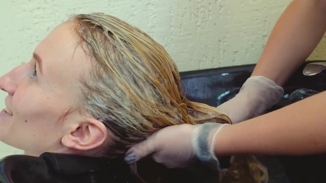 Hairdresser washes the hair of a young woman. Washing the blonde in the salon, makeup salon,hair dyeing process