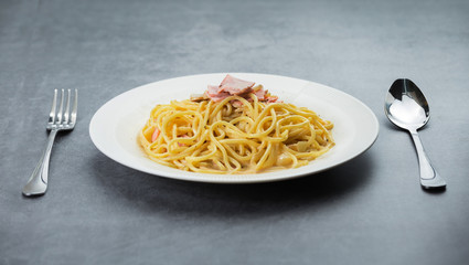 Spaghetti with ham cream sauce in white plate