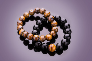 Bracelet from round stones lying on a mirror surface. Stone bead bracelets handmade from lucky stones. 
