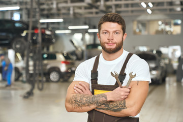 Brutal, muscular mechanic holding wrenches, posing.