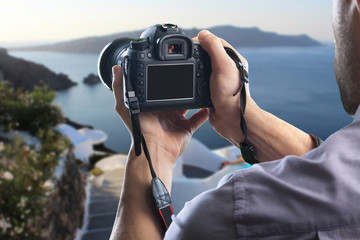 Young man holds modern digital black camera