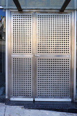 Entrance in modern building. Metal steel perforated doors.