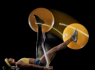 one mixed race woman exercising fitness exercises isolated on black background with lightpainting effect multiple exposures