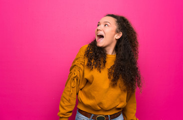 Teenager girl over pink wall smiling