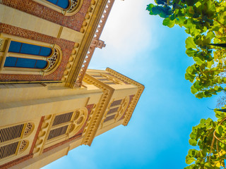 Low angle of the beautiful Christian church with clear blue sky and green leaves branches