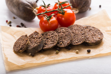 Food, meat and delicious concept - sausages made with horse meat with tomatoes on table