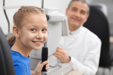 Patient, girl posing with doctor in optician office.