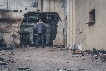 Confused man stands in a gap inside an old destroyed building