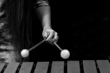 The hand of a girl playing a vibraphone in black and white