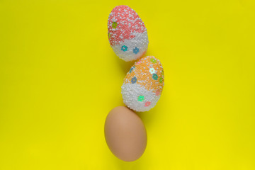 Three colorful decorated and real easter eggs on yellow pastel color background with copyspace. Easter concept, greeting card.
