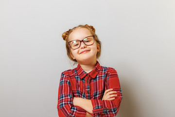 Portrait of a funny little preschool child girl in glasses on gray background. Concept education....