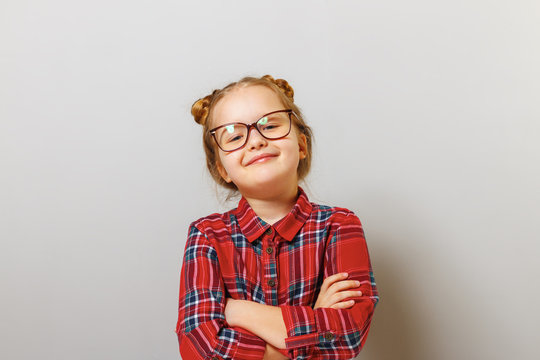 Portrait of a funny little preschool child girl in glasses on gray background. Concept education. Back to school.