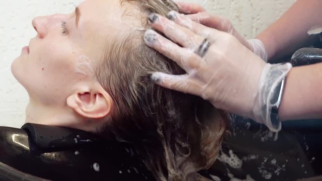 Hairdresser washes the hair of a young woman. Washing the blonde in the salon, makeup salon, hair dyeing process