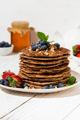 stack of homemade delicious pancakes for breakfast on white table, vertical