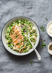 Healthy lunch -  orzo, green peas, spring herbs risotto and grilled chicken breast on a gray background, top view