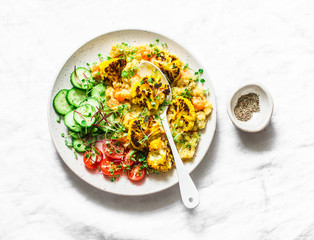 Pureed yellow pumpkin lentils, baked turmeric cauliflower and vegetables in one bowl - healthy vegetarian food on a light background, top view