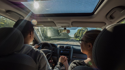 Multi-ethnic couple riding in a car, a man holding a woman's hand