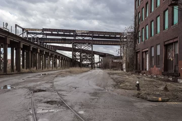 Foto op Plexiglas Oversteken van verhoogde treinsporen en oude verlaten fabriek van rode baksteen © Richard
