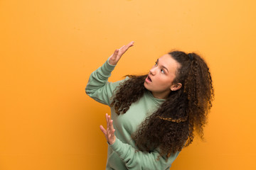 Teenager girl over ocher wall nervous and scared