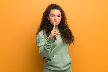 Teenager girl over ocher wall frustrated and pointing to the front
