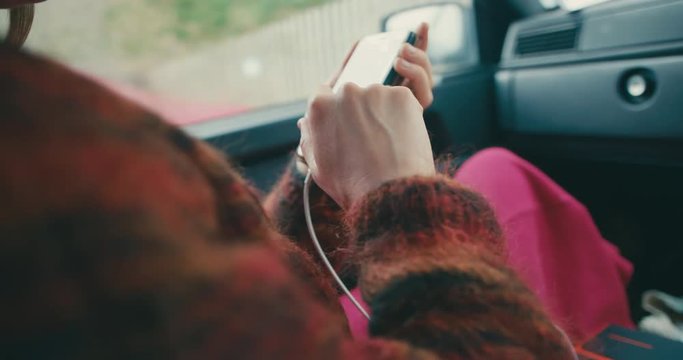 Young woman using smartphone in car while it's charging
