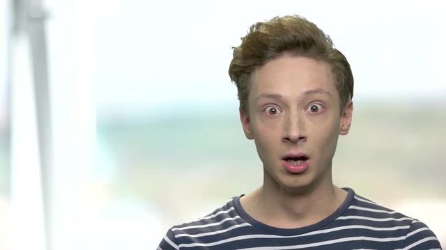 Portrait of young boy with shocked expression. Close up scared teen guy on blurred background. Human expression of fear.