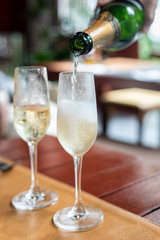 Bartender pouring champagne into glass, Two bright icy champagne glasses, confetti falling and sparklers