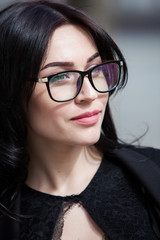 Elegant woman looking at camera in the black dress with glasses portrait of a beautiful hipster girl in glasses Concept: beautiful eyes, beautiful smile, vision, perfect skin