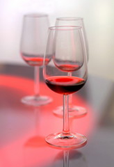 Three glasses of red wine on bright color background.