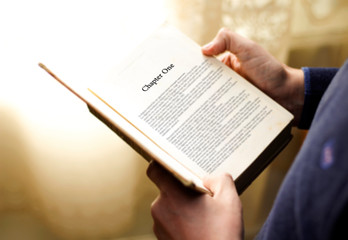 man's hand on book page with title 