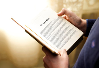 Naklejka premium man's hand on book page with title 
