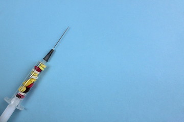 On a blue background lies a syringe inside which are tablets