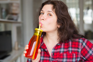 Health, food, diet and people concept - young woman drinking natural juice in a bottle and it seems to be tasty