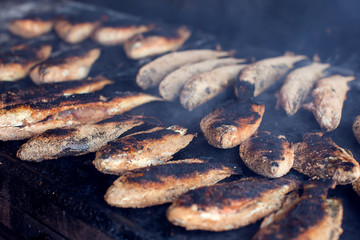 A lot of fish on the grill. Street food cooking process