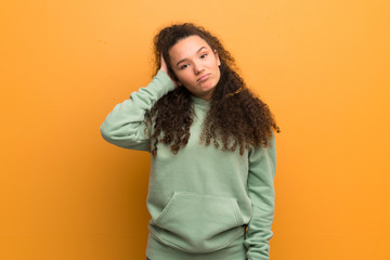 Teenager girl over ocher wall with an expression of frustration and not understanding