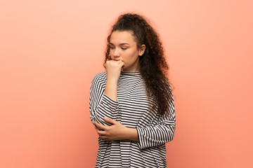 Teenager girl over pink wall having doubts