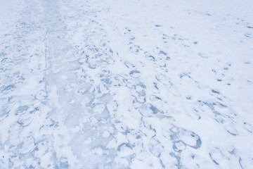 Footprints on the surface of a frozen lake. Frosted water and snow. Footpath on a frozen lake....