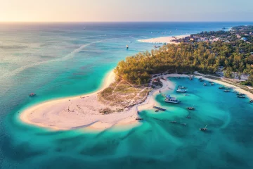 Abwaschbare Fototapete Zanzibar Luftaufnahme der Fischerboote an der tropischen Küste mit Sandstrand bei Sonnenuntergang. Sommerurlaub am Indischen Ozean, Sansibar, Afrika. Landschaft mit Boot, grünen Bäumen, transparentem blauem Wasser. Ansicht von oben