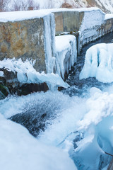 Frozen water channel. Mountain river in winter. Icing on the bank of the stream. Bypass channel....