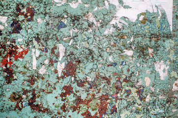 A fragment of the wall, covered with a layer of old cracked paint, with traces of pasted paper, in smooth daylight.