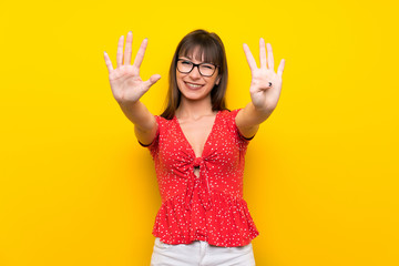 Young woman over yellow wall counting nine with fingers