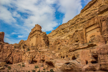 picturesque sandstone Middle East rocks from below on vivid blue sky background and ancient temple building carved in yellow stone Petra famous heritage touristic and archeological site 
