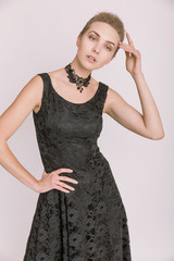 Fototapeta premium Portrait einer jungen Frau in schwarzem Kleid vor hellem Hintergrund