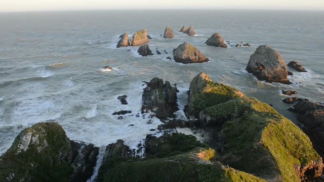 Setting sun illuminates boulders and waves of Nugget Point