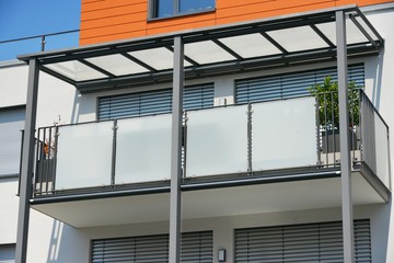 Balkon mit verglastem Edelstahl-Geländer an der Fassade eines modernen Wohnhauses