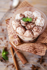 tiramisu in a glass cup decorated with cocoa powder and mint leaves