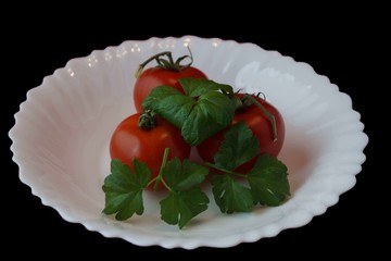 tomatoes and green celery on a black background