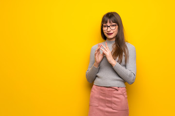 Woman with glasses over yellow wall scheming something