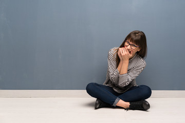 Woman with glasses sitting on the floor smiling a lot